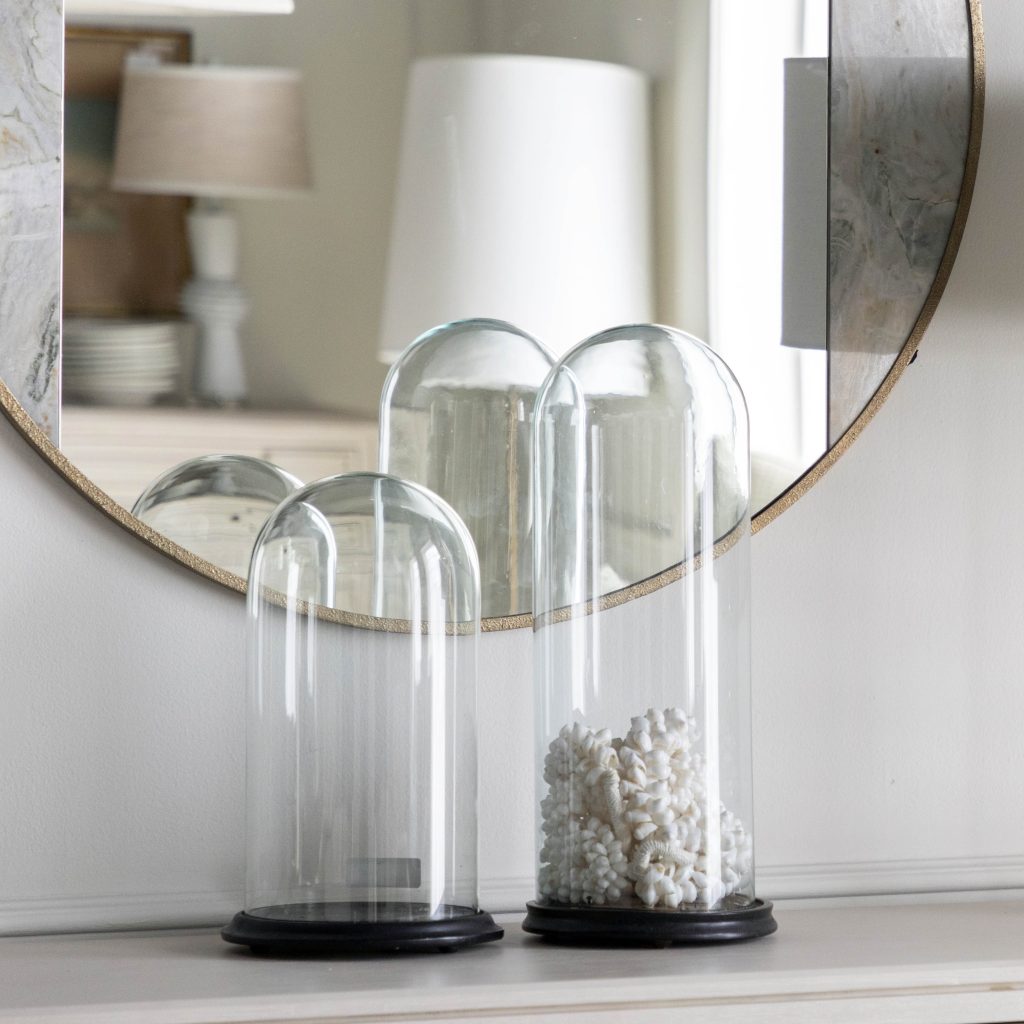 A selection of antique glass cloches in front of a mirror reflecting an elegant room