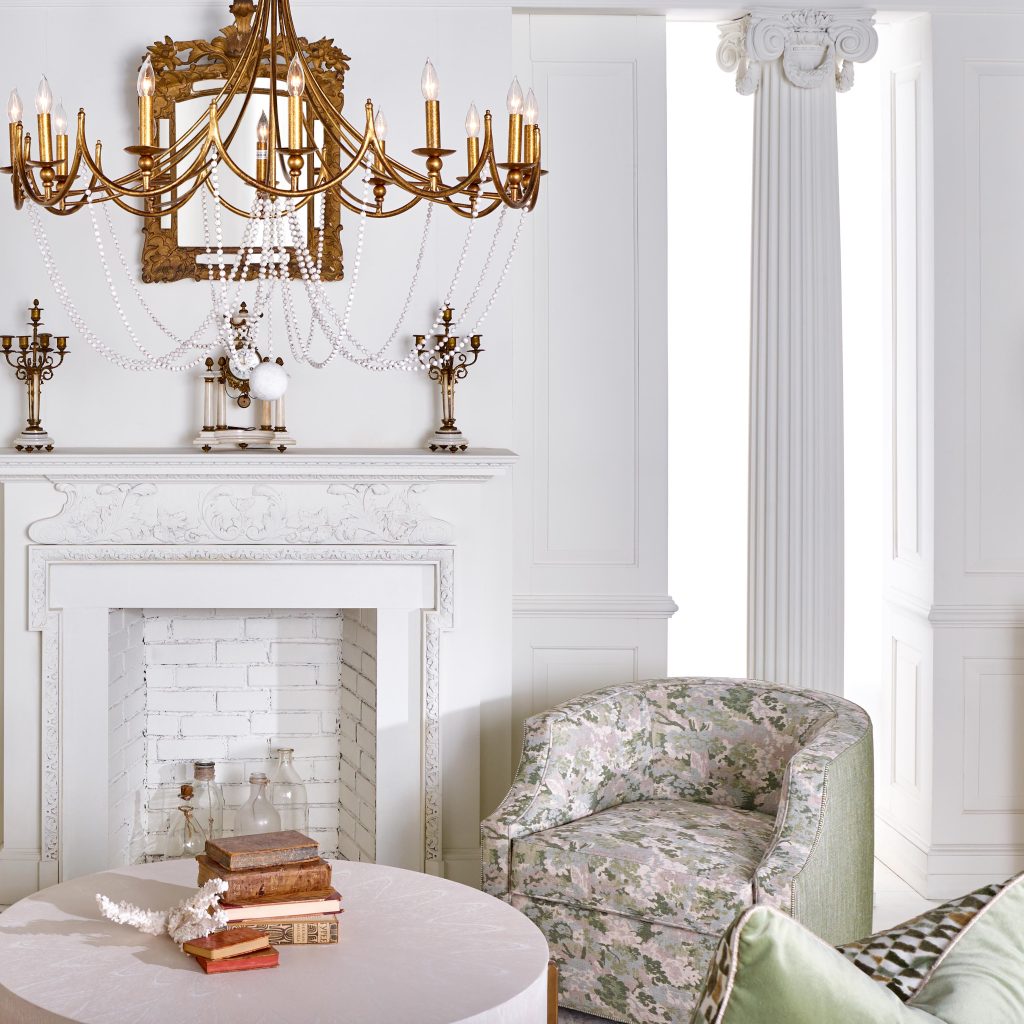 A sophisticated sitting room with French mantelpiece, white columns and architectural details, a pair of small green upholstered swivel chairs.